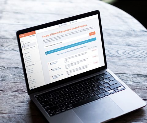 Photo of a laptop on a wooden table displaying Athabasca University’s online course catalog, showing a well-organized and intuitive interface that renders a complex database into a simple, user-friendly experience.