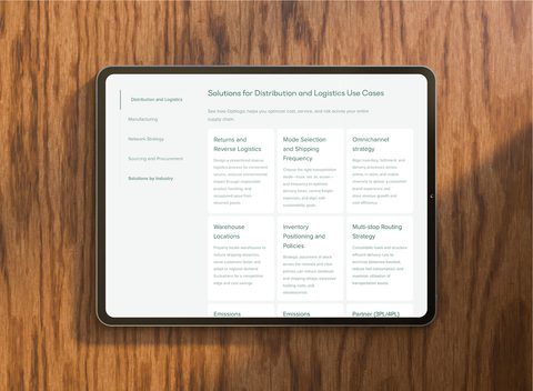 Photo of a tablet on a wooden surface displaying the Optilogic website, with a page outlining solutions for distribution and logistics use cases with a clean and intuitive interface.