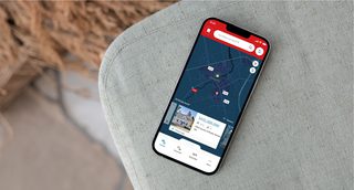 Photo of a smartphone on a fabric surface displaying the REALTOR.ca mobile app, showing a property search map with listing details, price, and photos—demonstrating an intuitive, user-friendly interface for real estate browsing.